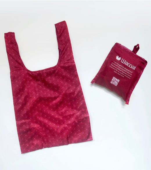 A reusable shopping bag made of textured, stretchy fabric in a deep magenta-red color, shown next to its small, folded branded storage pouch. The pouch features the 'Warcoal' brand name and logo in white.